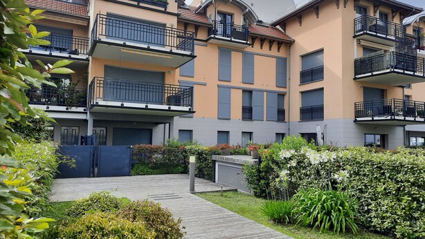 A multi-story residential building with balconies, a paved walkway, and well-maintained greenery. - Large apartment with private garden (Arcachon)