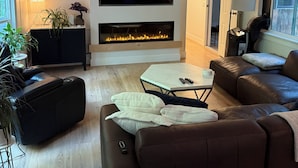 A modern living room with a fireplace, leather sofa, and a flat-screen TV.