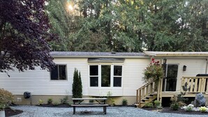 A well-maintained backyard with artificial grass, a picnic table, and a small deck.