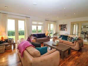 A spacious living room with two sofas, a coffee table, and a bookshelf. - 25 RING OF KERRY GOLF CLUB COTTAGES in Kenmare, County Kerry (Kenmare)