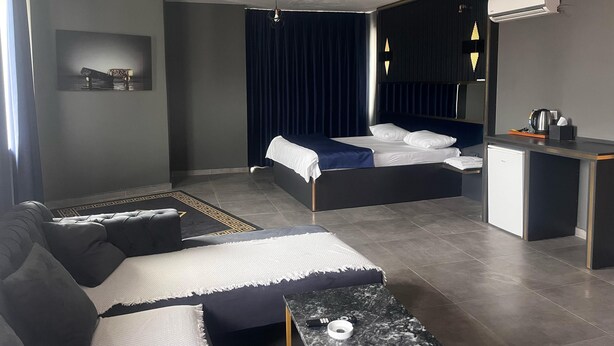 Ein modernes Hotelzimmer mit Bett, Sofa, Schreibtisch und einer Kaffeemaschine.