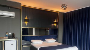 Ein modernes Hotelzimmer mit Bett, Nachttisch und kleinem Kühlschrank.