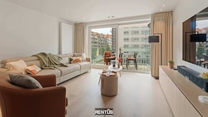 A modern living room with a sofa, coffee table, and a dining area with chairs.