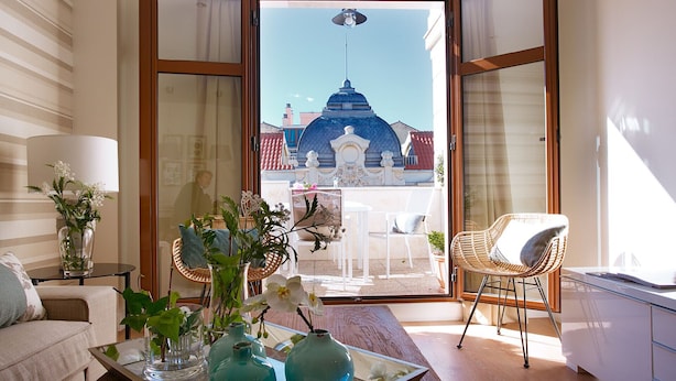 Una sala de estar moderna con vista a un edificio azul con cúpula a través de puertas de vidrio.