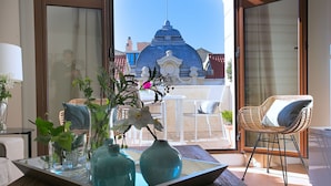 Una habitación con una mesa de vidrio, sillas blancas y vistas a un edificio con cúpula azul.