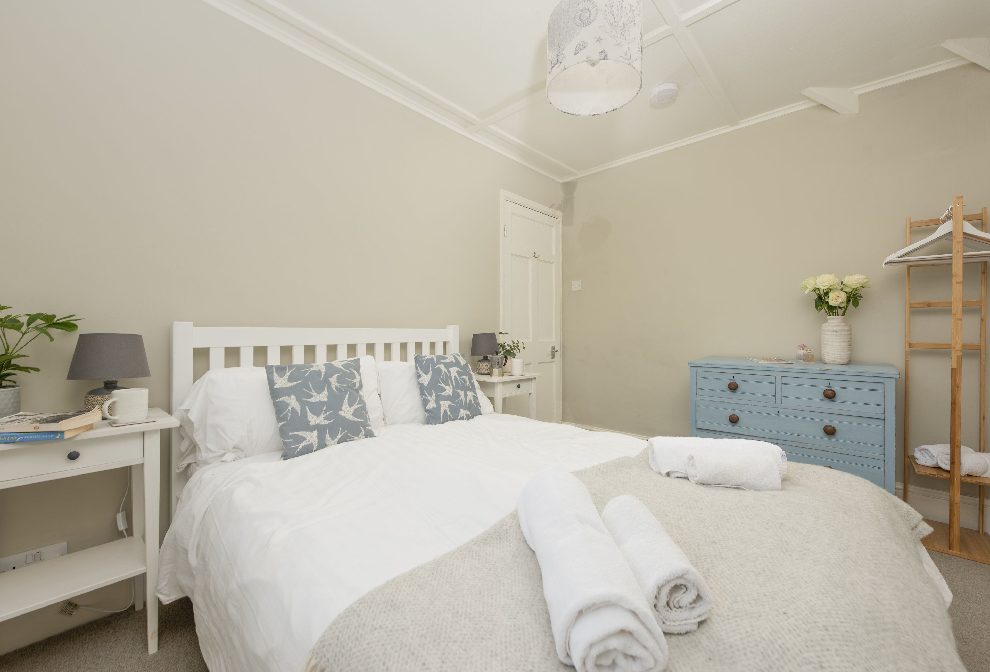 Une chambre bien rangée, avec un lit, des tables de chevet, une commode et un portant à vêtements.