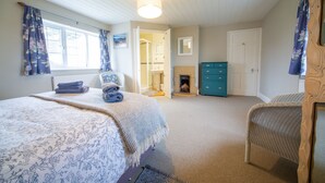 A bedroom with a bed, a chair, a dresser, and a fireplace.