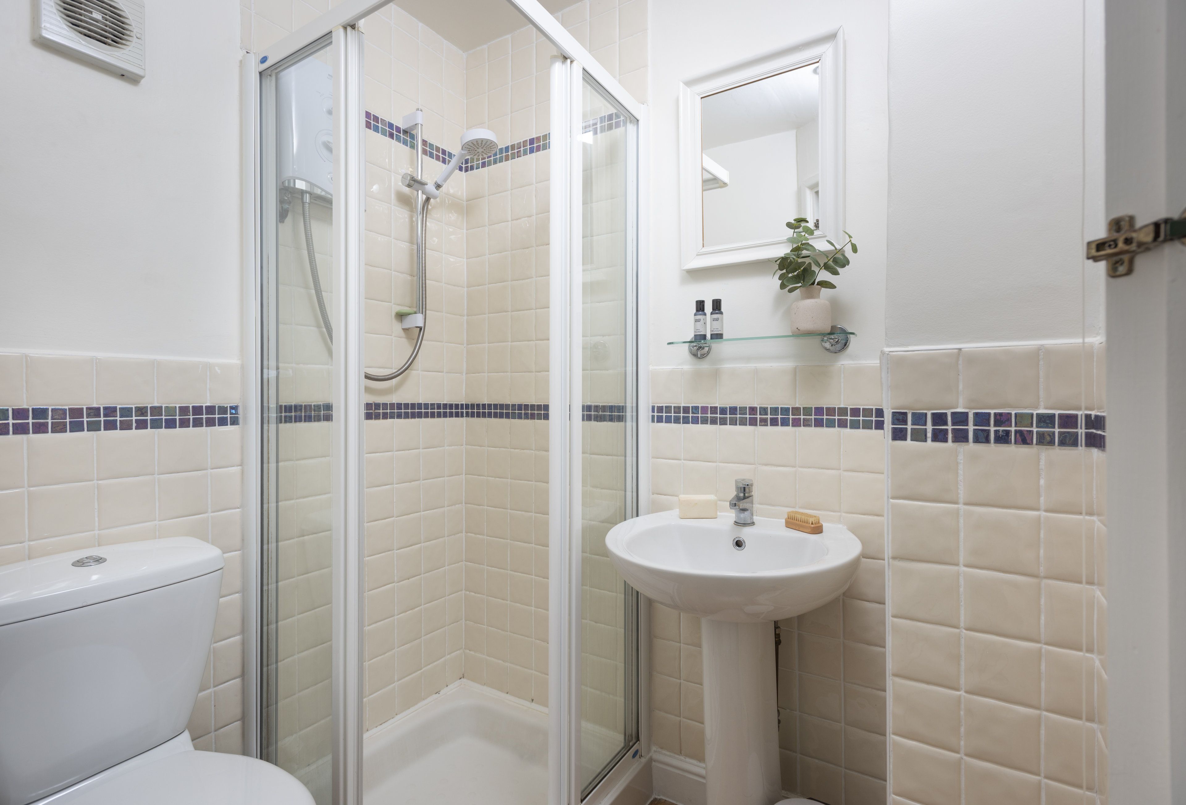 Ein Badezimmer mit einer Duschkabine, einem weißen Waschbecken und einer Toilette.