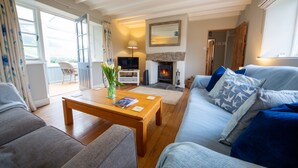 A living room with a sofa, a coffee table, a fireplace, and a television.