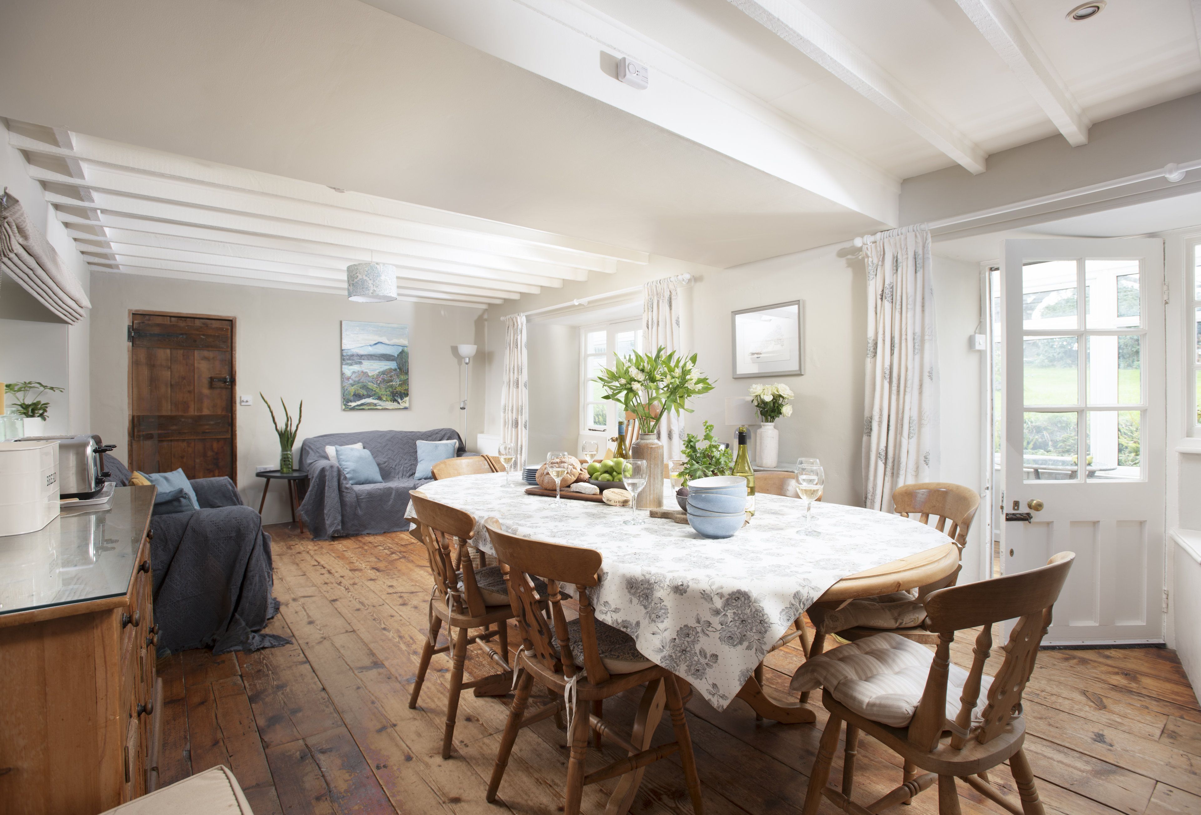 A dining room with a round table, wooden chairs, and a white ceiling.