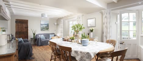 A dining room with a round table, wooden chairs, and a white ceiling.