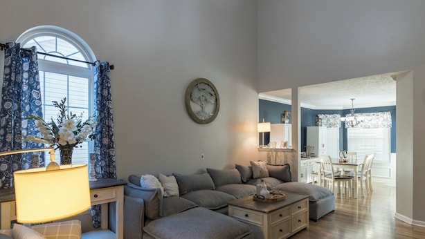 A living room with a sectional sofa, ottoman, and a dining area with a table and chairs. - Scenic View by the Pond in Lexington (Lexington)