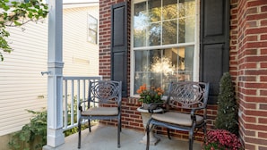 A porch with two metal chairs and a potted plant. - Scenic View by the Pond in Lexington (Lexington)