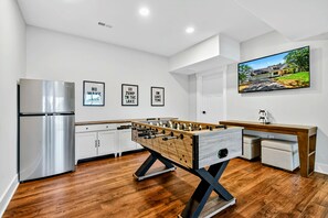 A modern kitchen with a foosball table, a refrigerator, and a wall-mounted TV.