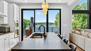 Une cuisine moderne dotée d’un grand îlot central, d’un coin repas et offrant une vue sur un lac.