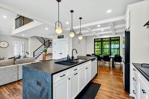 Kitchen - Open layout shows the island, staircase to the loft, and cozy dining nook with coffered ceiling.