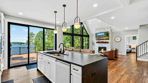 Une cuisine moderne dotée d’un grand îlot central, d’une cheminée et offrant une vue sur l’extérieur.
