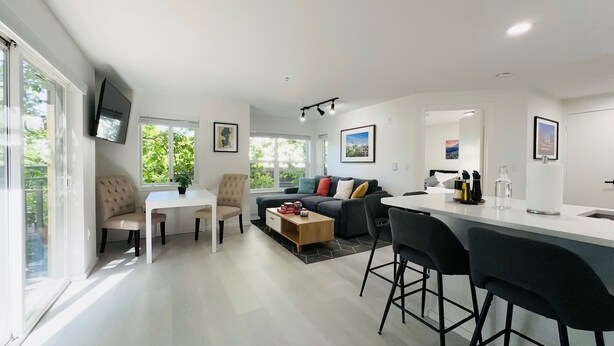 A modern kitchen and living area with a dining table, bar stools, and a sofa. - 0.3 Miles to Space Needle! 2Br/2Ba Belltown Condo w/ Free Garage Parking + AC (Seattle)