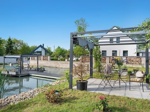 Un espacio exterior tranquilo con piscina, pérgola y patio amueblado.