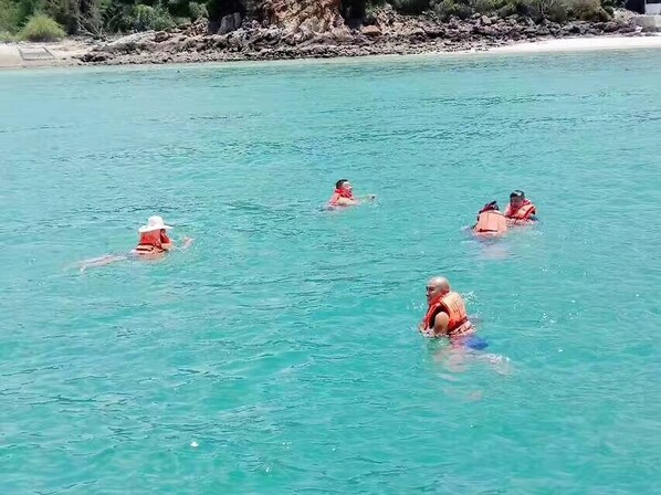 A group of people in the water wearing life jackets.