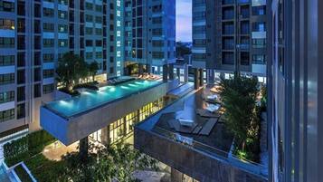 A high-rise building with multiple balconies and a rooftop swimming pool.