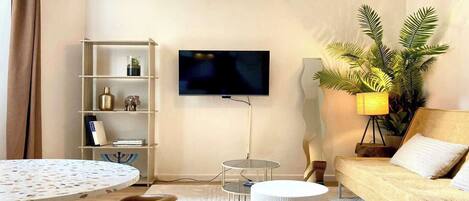 A living room with a sofa, a TV, a bookshelf, a round table, and a lamp.