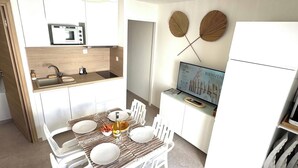 A compact kitchen with a microwave, sink, and a dining area with a table set for two.