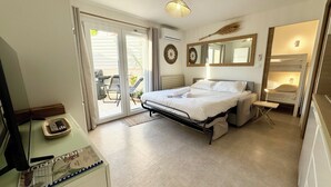 A bedroom with a bed, a desk with a computer, a chair, and a sliding glass door leading to an outdoor area.
