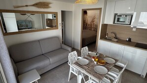 A compact living space with a kitchenette, a dining area with a table and chairs, and a sofa.