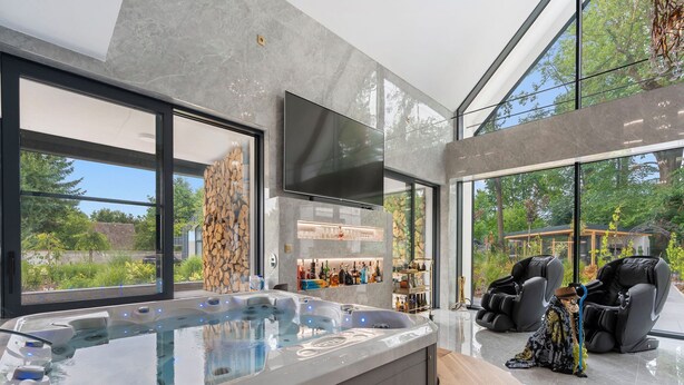 A modern spa area with a hot tub, massage chairs, and a bar.
