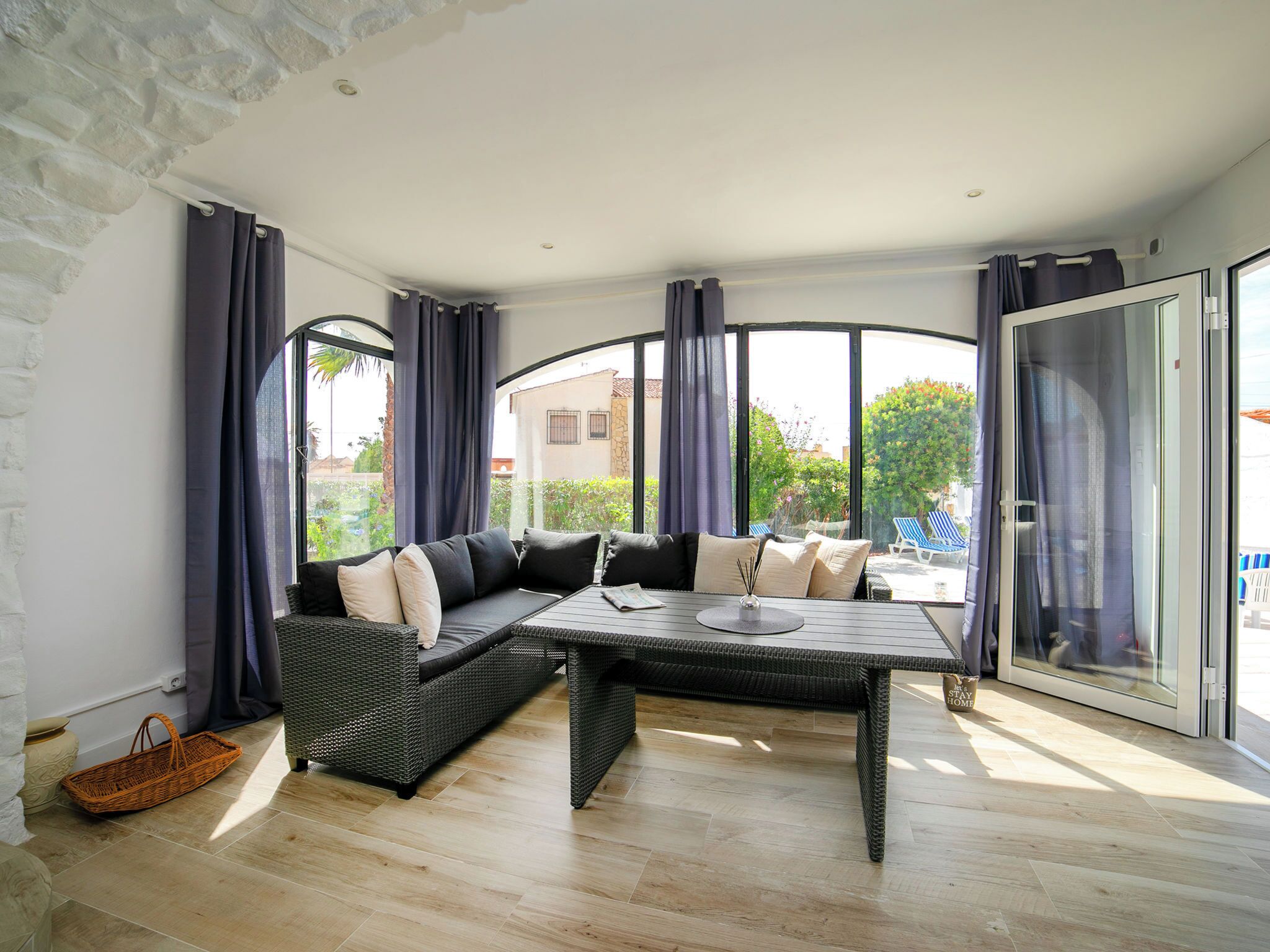 A modern living room with a sectional sofa, a glass door leading to a balcony, and a view of the outside.
