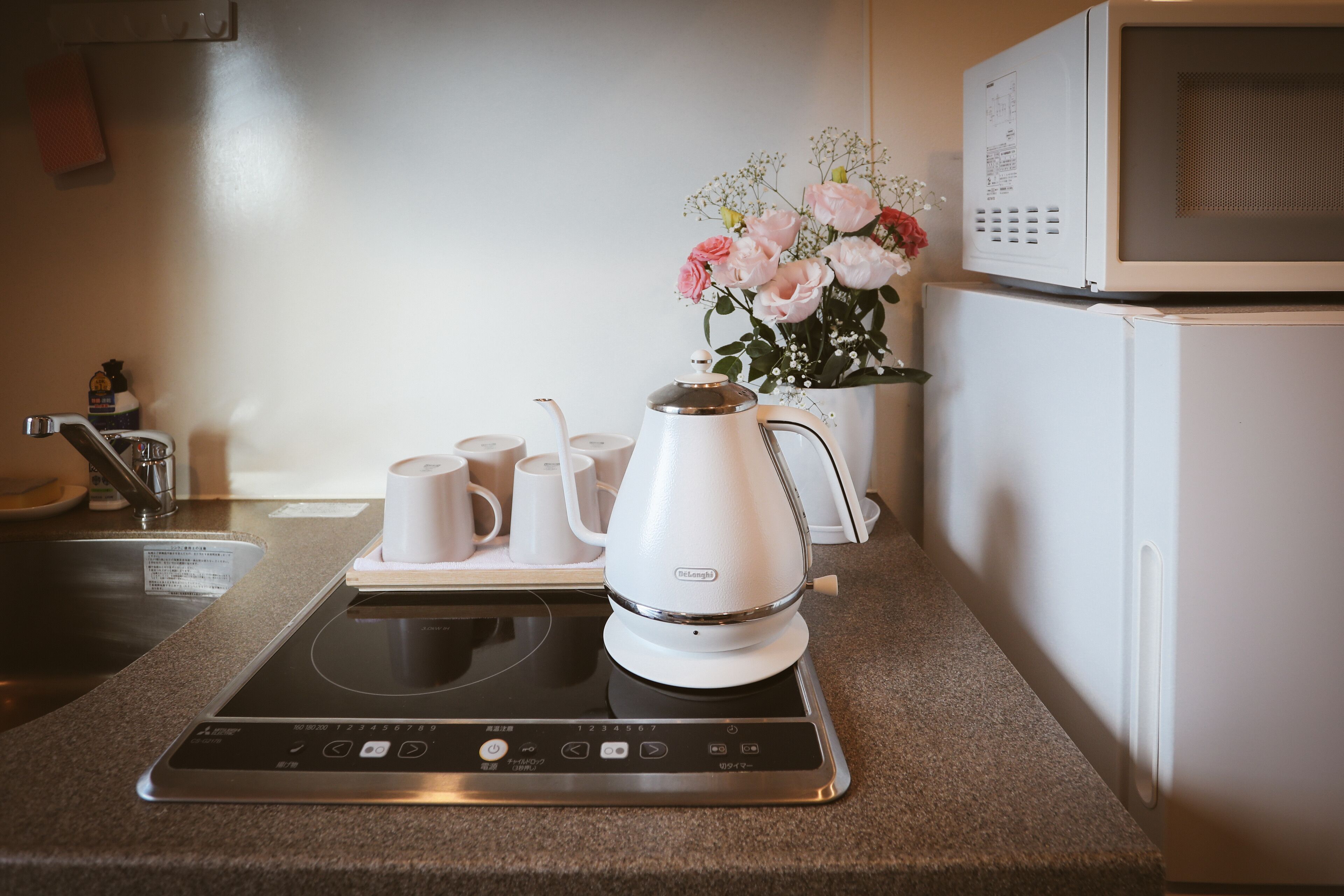 A kitchen with a built-in induction cooktop, a microwave, and a coffee maker.
