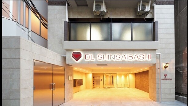 Entrada de um edifício moderno com uma placa que diz "DL SHINSAIBASHI".