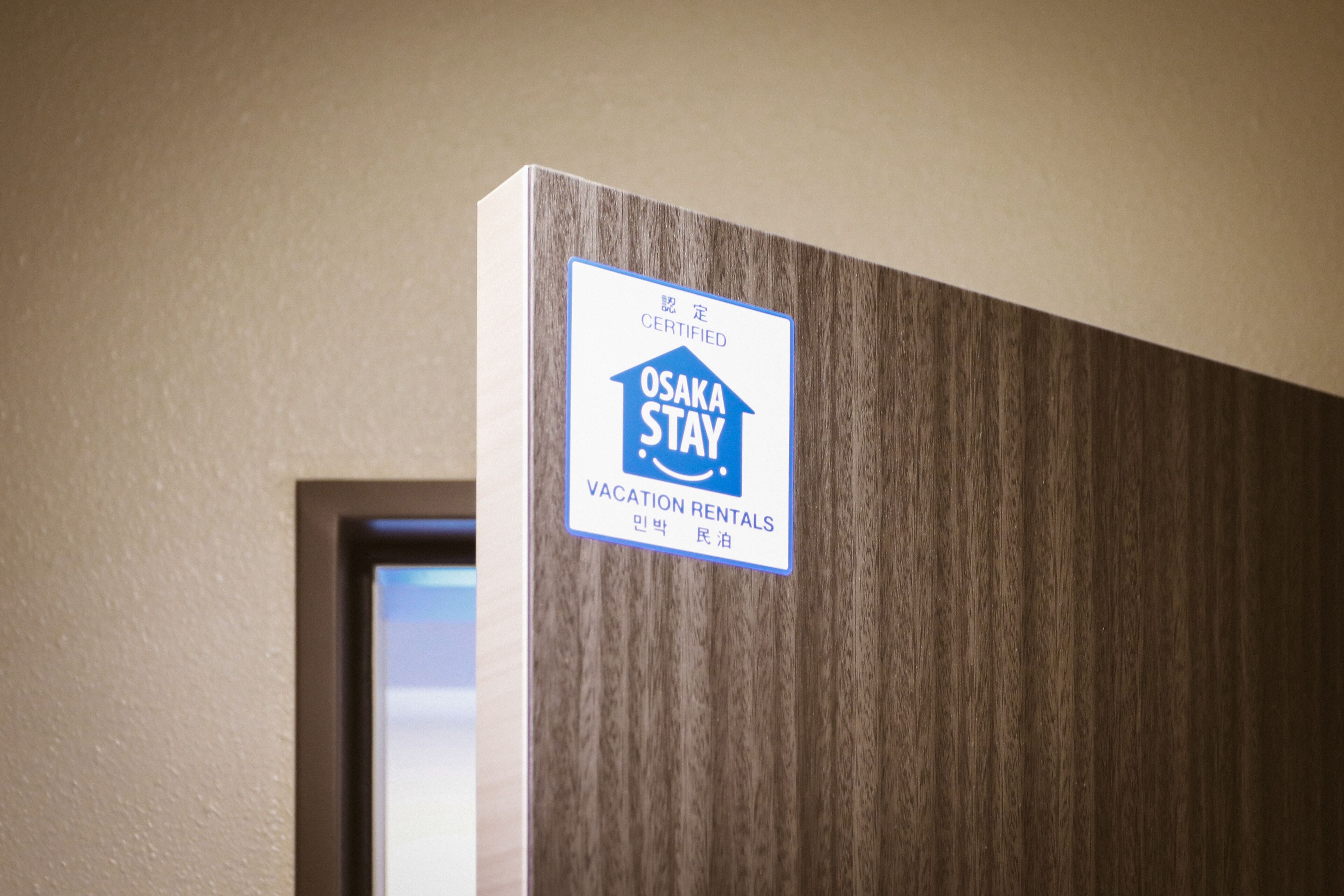 A door with a sign indicating it is a certified Osaka Stay vacation rental.