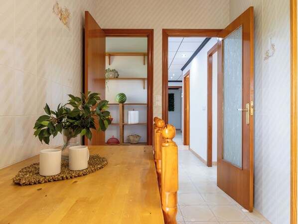 A hallway with a wooden floor, a potted plant, a wooden bench, and a traditional Japanese sliding door.