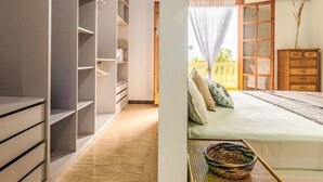 A bedroom with a large wardrobe, a bed with pillows, a wooden dresser, and a window with a view of greenery. - Corbella by Interhome (Deltebre)