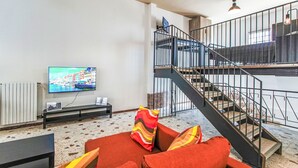 Ein Wohnzimmer mit Fernseher, einer Couch und einer Treppe.