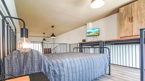 Ein Schlafzimmer mit einem Bett, einem Schreibtisch, einem Fernseher und einem Holzschrank.