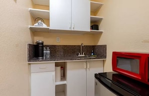 A compact kitchenette with a microwave, a coffee maker, and a sink.