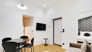 Ein modernes Wohnzimmer mit Essbereich, einem Flachbildfernseher und einer Wand mit Musterdesign.