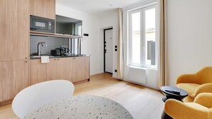 Une cuisine moderne équipée d’un four à micro-ondes, d’une machine à café et d’un évier. Un coin repas avec une table et des chaises est également à disposition.