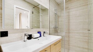 Une salle de bain moderne avec un grand lavabo blanc, une cabine de douche en verre et un miroir au-dessus du lavabo.
