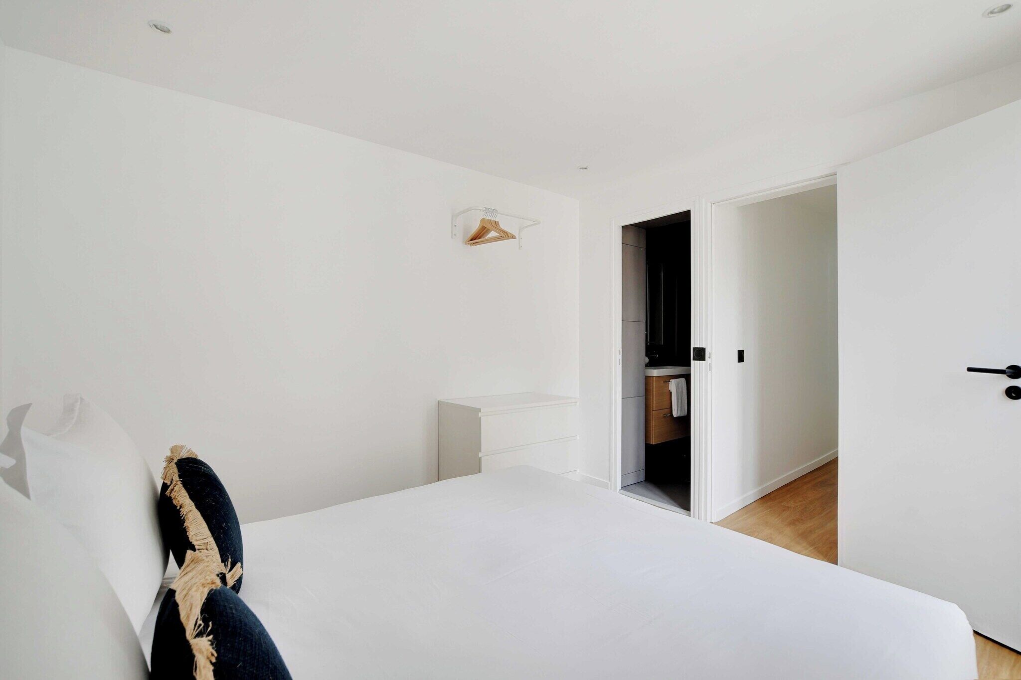 Una camera da letto con un letto, un armadio bianco, una porta che conduce al bagno e un piccolo ripiano.
