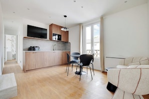Una cocina moderna con armarios de madera, televisor integrado y un comedor con mesa y sillas.
