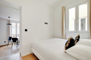 Un dormitorio con una cama, una ventana y una puerta que da a otra habitación.