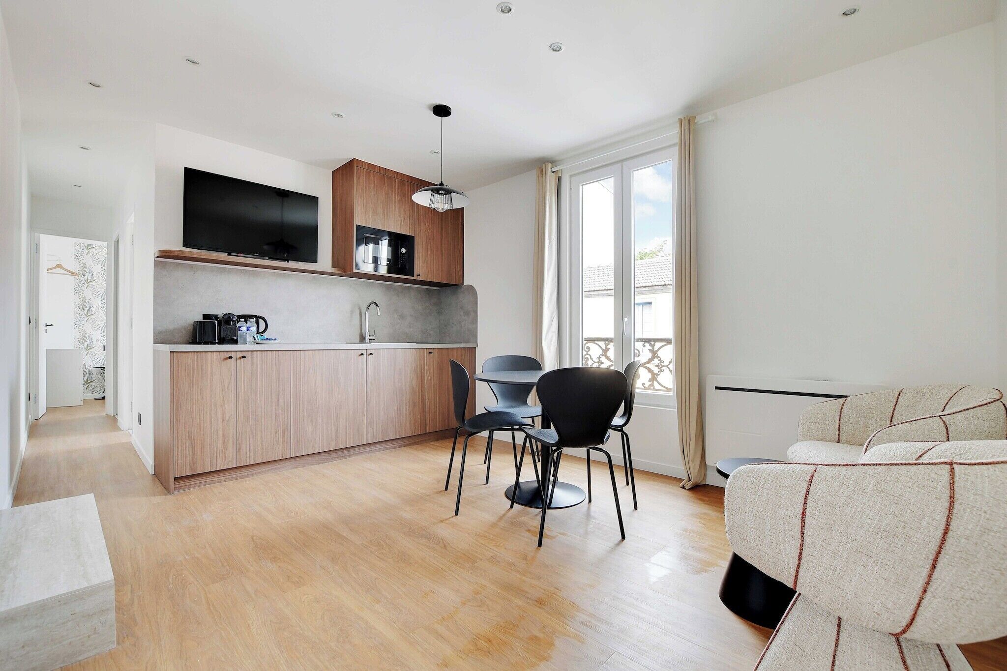 Een moderne keuken met houten kastjes, een ingebouwde televisie en een eetgedeelte met een ronde tafel en stoelen.