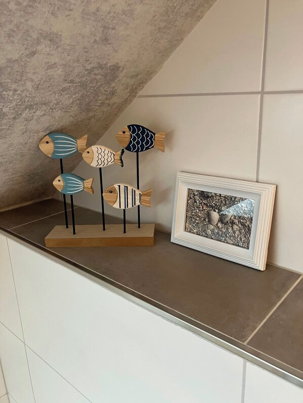 Un comptoir de cuisine orné d’un tableau représentant des coquillages et d’une décoration en forme de poisson en bois.