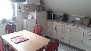 A small kitchen with a dining table, chairs, and basic appliances.