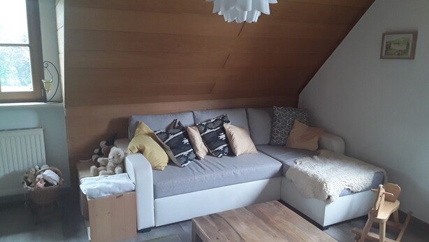 A cozy loft-style living room with a sectional sofa, a wooden coffee table, and a rocking chair.