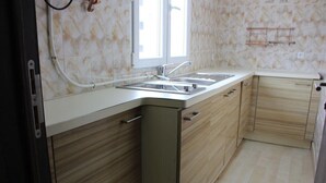 A kitchen with a double sink, wooden cabinets, and a window. - Saint David Hôtel Résidence (Douala)